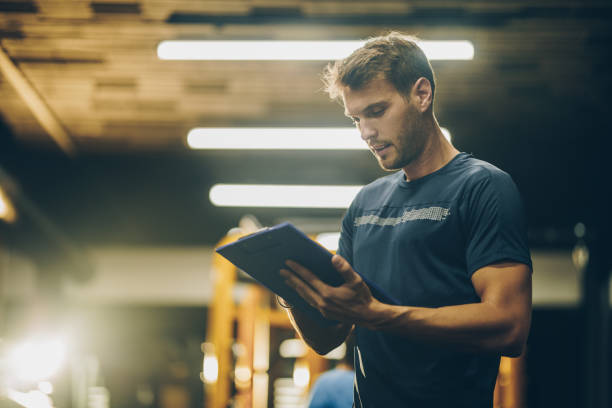 Young coach making a training plan in a gym.